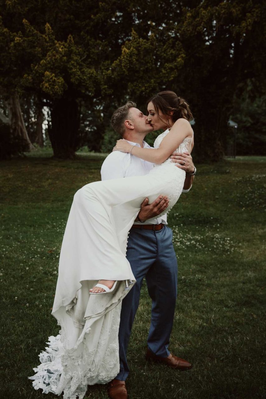 Groom holdin gbride in the air and kissing at dusk