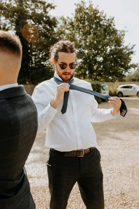 Groosman laughing while doing his tie on a beautiful sunny morning