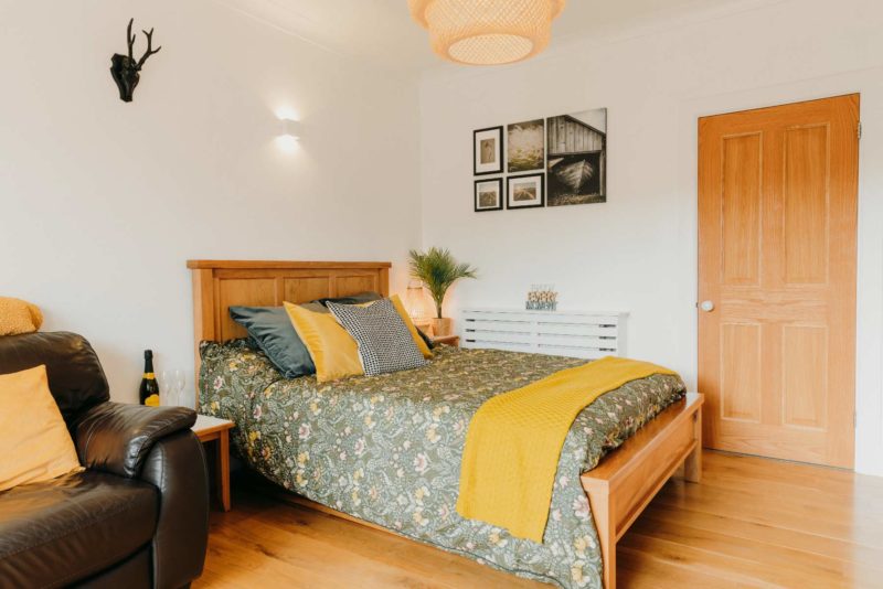 Property photography featuring a small studio with bed and sofa with yellow cushions
