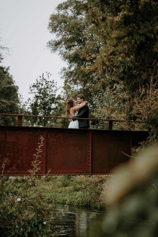 Happy couple stood on an old iron bridge