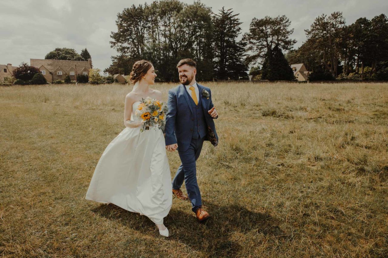 Happy couple walking hand in hand through a field on a gorgeous sunny day
