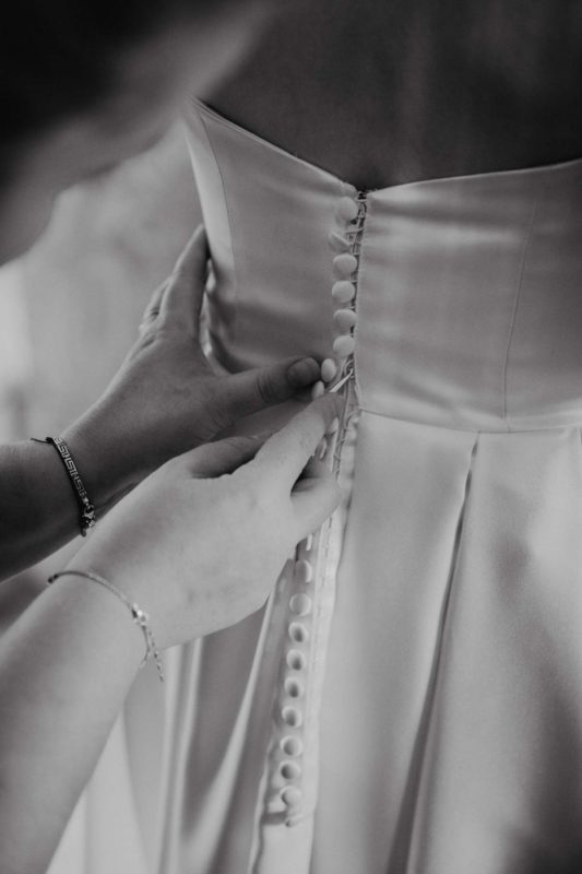 A wedding dress being done up from behind in black and white