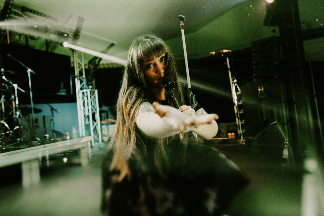 Dream State frontwoman Jessie knelt on stage singing into the camera. Shot in Swanea Patti Pavillion on the Still Dreaming UK tour.
