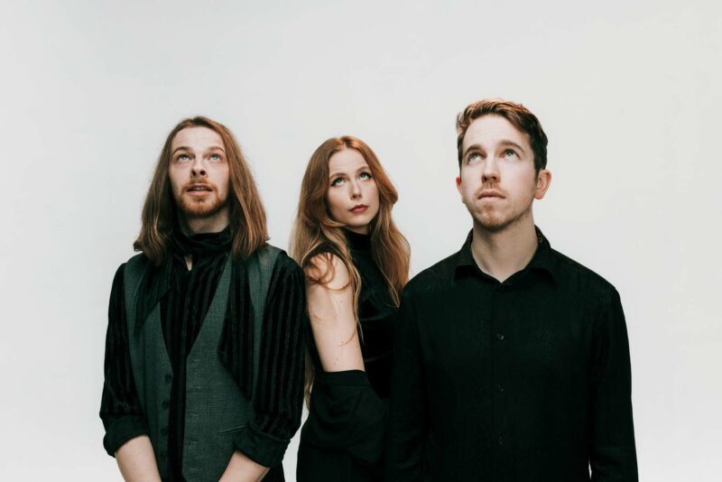 Rock band trio, Mythora, shot against a plain white studio backdrop at Firebug Studios.