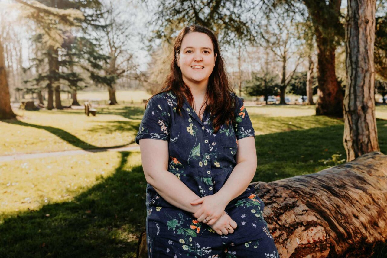 Portrait of author Hannah Hendy sat in Caldicot Castle country park on a sunny spring morning. 