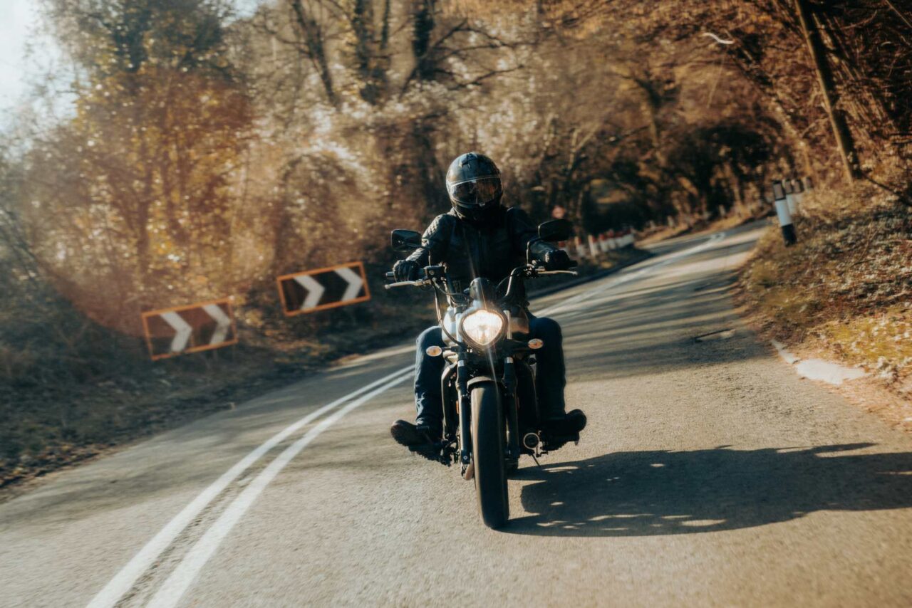 Action shot of a lone motorcycle rider sweeping around a country road towards the camera on a Kawasaki Vulcan. Shot on a sunny winter morning in the Wye Valley.
